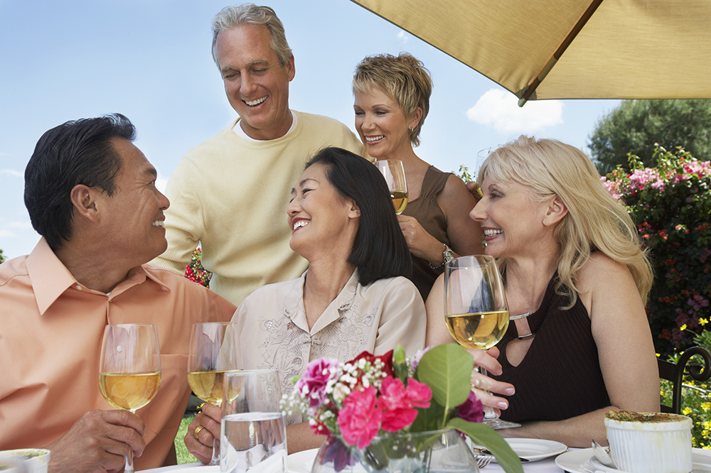 photo of a group of baby boomers sitting together at an outdoor party drinking alcohol