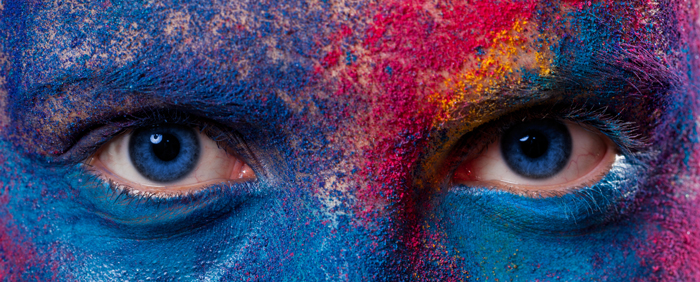 photo of a closeup of person's eyes and forehead covered in many different color paints