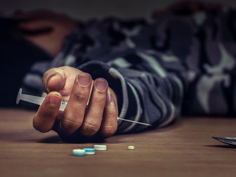 person lying on the ground holding drugs