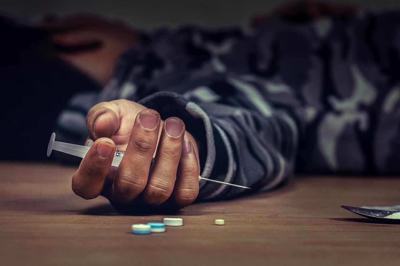 person lying on the ground holding drugs