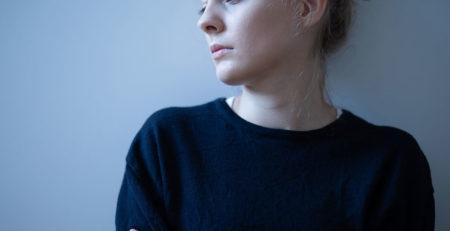 woman in a blue shirt leaning the wall