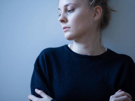 woman in a blue shirt leaning the wall