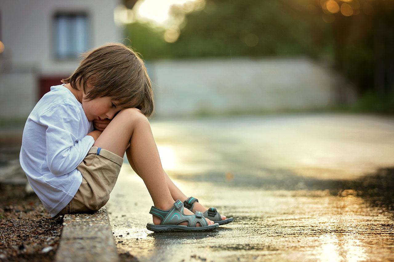 child sitting on street walk