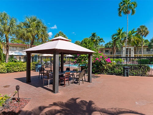 Shaded outdoor gazebo and seating area beside the facility pool